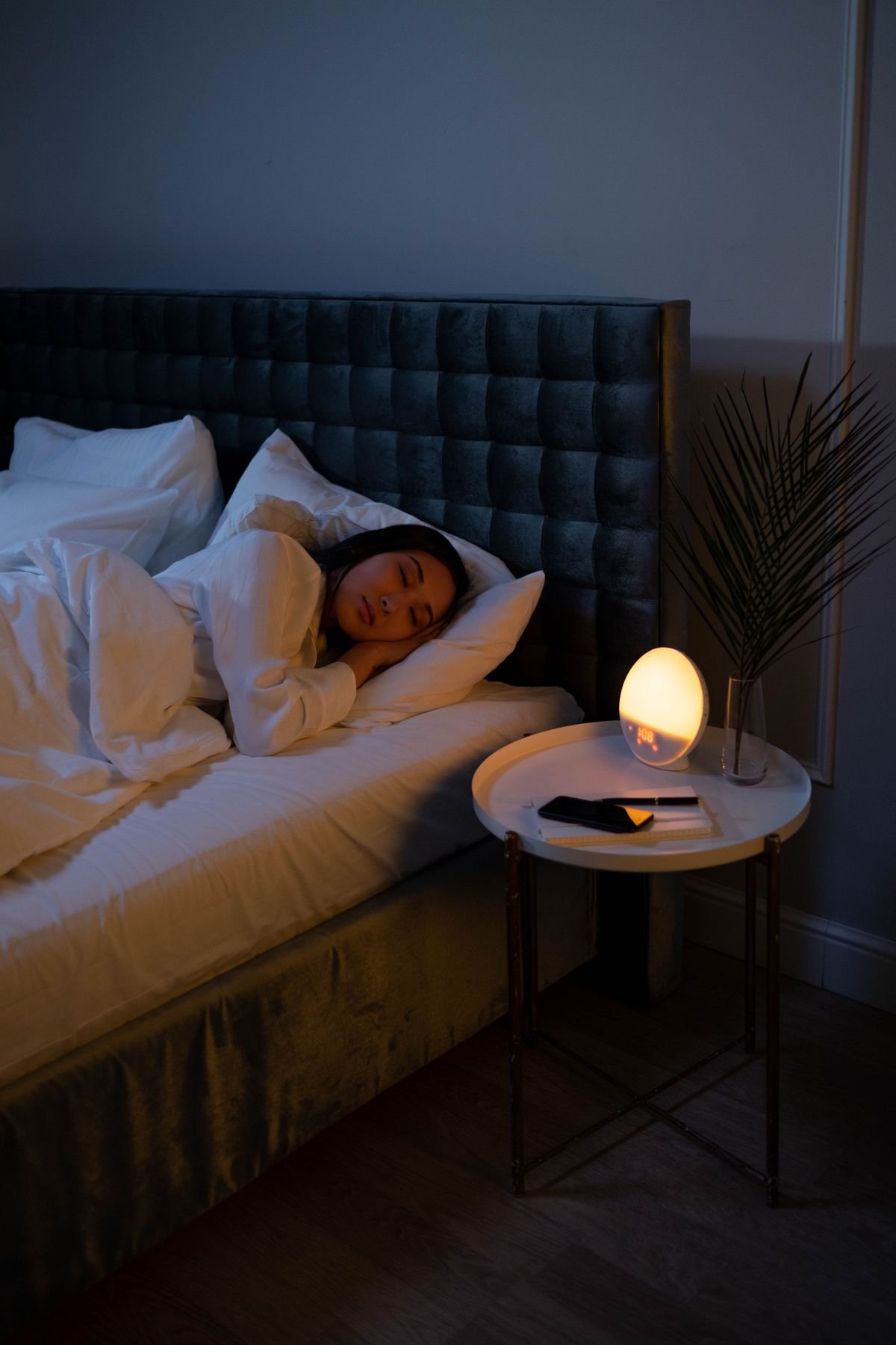 Mujer durmiendo plácidamente en su cama de noche junto a una luz tenue